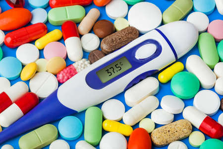 Pills and electronic thermometer (37.5 degrees) - abstract medical background