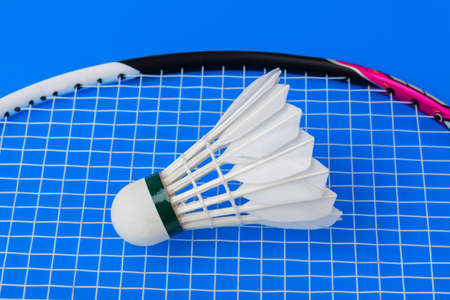 Badminton shuttlecock and racket on blue - sport background