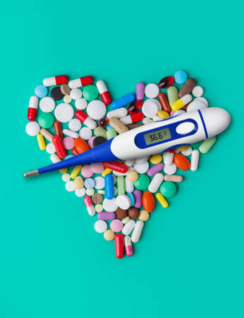 Thermometer and heart made of pills - abstract medical background