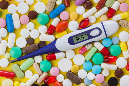 Pills and electronic thermometer (36.6 degrees) - abstract medical backgroundの写真素材
