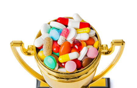 Golden trophy cup with pills isolated on white backgroundの写真素材