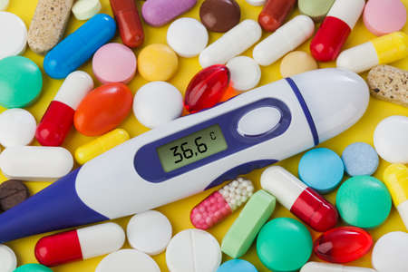 Pills and electronic thermometer (36.6 degrees) - abstract medical background