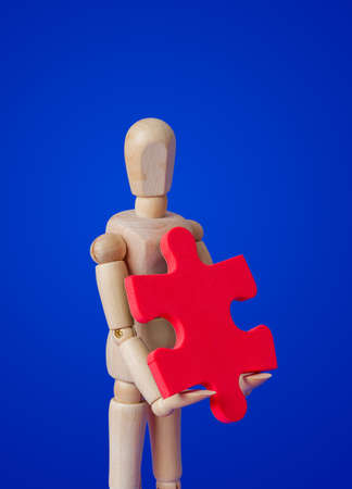Wooden toy figure with puzzle on blue backgroundの写真素材