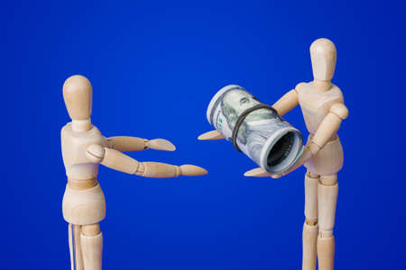 Wooden toy figures with money on blue backgroundの写真素材