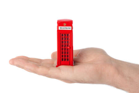 Hand with toy red phone booth of London isolated on white background