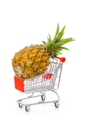 Ripe pineapple in shopping cart isolated on white backgroundの写真素材