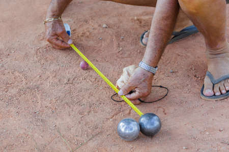 Man measures distance between balls during petanque game - sport backgroundの写真素材