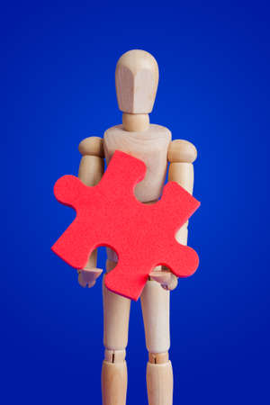 Wooden toy figure with puzzle on blue backgroundの写真素材