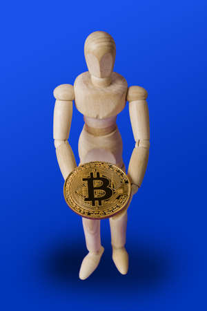 Wooden toy figure with bitcoin on blue backgroundの写真素材