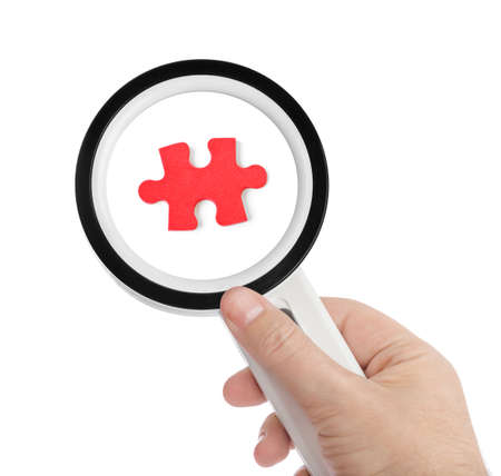 Hand with magnifying glass and puzzle isolated on white background