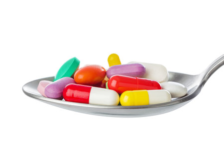 Spoon with pills isolated on white background
