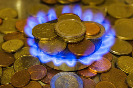Coins of on the gas burner of the kitchen stove - business background