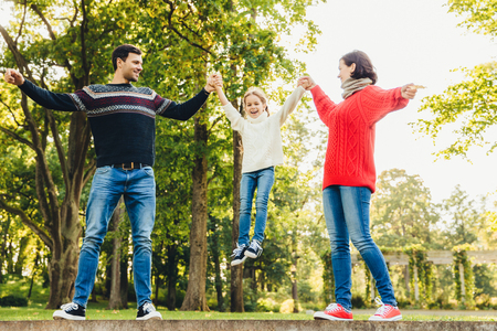 Excited small child being glad to have time with her parents, rocks in their hands, smiles happily.の写真素材