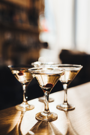 Few transparent shiny glasses filled with alcoholic cocktails and served on wooden counter on party. の写真素材