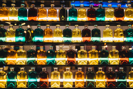Different colored glass bottles standing on shelves with illumination. の写真素材