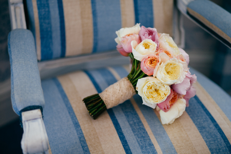 Wedding symbol. Wonderful wedding bouquet lies on vintage armchair, prepared for special occasion. Flowersの写真素材