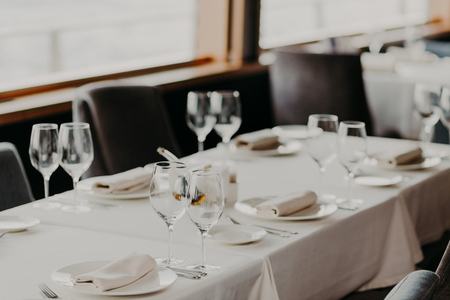 Catering and celebration concept. Festive served dinner table with glasses and cutlery on white...