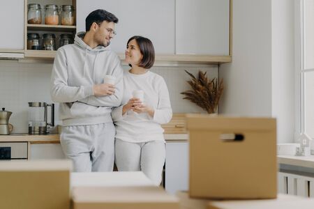 Image of cheerful woman and man have pleasant talk during coffee break, wear casual clothes, move in...