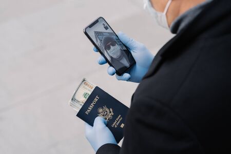 Shot of unrecognizable man follow rules of social distancing, makes video call, holds mobile phone,...