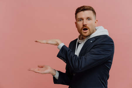 Amazed shocked man in stylish casual outfit showing approximate size of product with hands,...