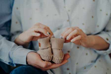 Newborn baby boots. Cropped shot of future woman and man ready to become parents holds childrens...