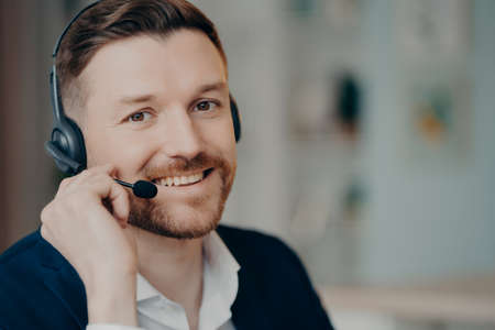 Happy young business professional or executive manager wearing suit and headphones with microphone...