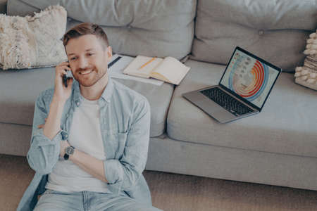 Happy young man calling family to inform about receiving promotion at his company after submitting...