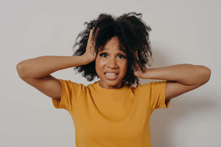 African American distressed young woman losing control over emotions, closing her ears with hands tightly, showing I can not stand it anymore gesture. Isolated over white background with copy spaceの写真素材