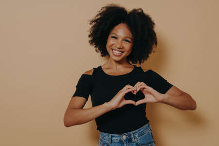 African american woman wearing casual clothes showing love gesture with heart shaped fingers,...