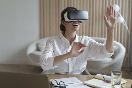 Cyberspace in business. Happy woman office worker wearing vr goggles, touching objects with hands in...