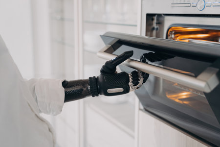 Handicapped person's robotic cyber hand opens oven in the kitchen, ready to bake.の写真素材