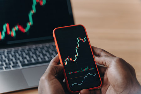 African hands holding smartphone and laptop, analyzing financial data graphs, trading stock market, investment purposes.の写真素材