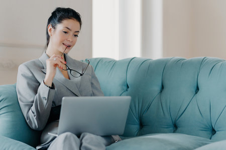 Serious entrepreneur analyzes data on laptop, takes off glasses, works online in coworking space.の写真素材