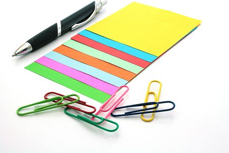 Colour paper clips and colour scratch paper with the handle on a table.