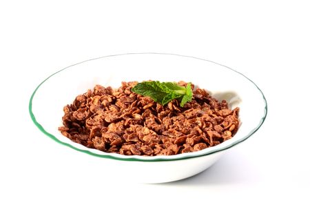 Chocolate cereals in a white soup plate without milk with a mint leaf.の写真素材