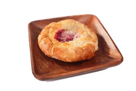 The rich is sweet a roll from the white test with jam in the middle on a wooden plate.の写真素材