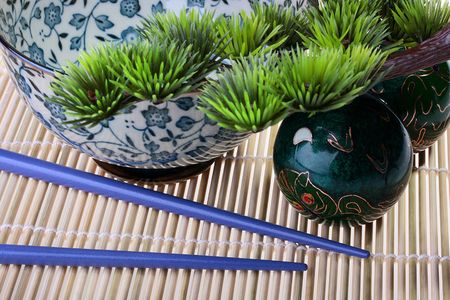 Subjects belonging to east culture: a bamboo laying, a small tree, spheres for meditation, sticks and a deep cup for meal.の写真素材