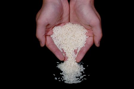 Man's hands pouring out rice on a black background.の写真素材