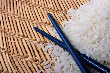 Rice on a straw mat with chopsticks.の写真素材