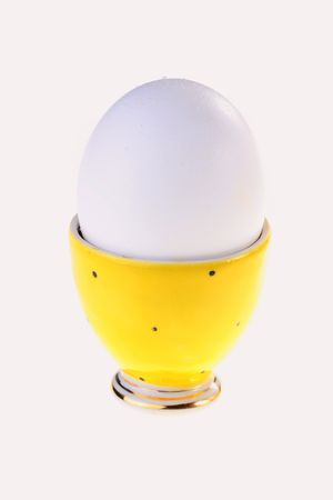 Egg in a yellow support for eggs on a white background.の写真素材