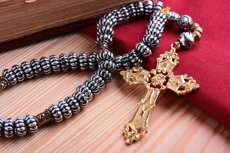 Religion. A cross with a chain against a wooden table and a red fabric.の写真素材