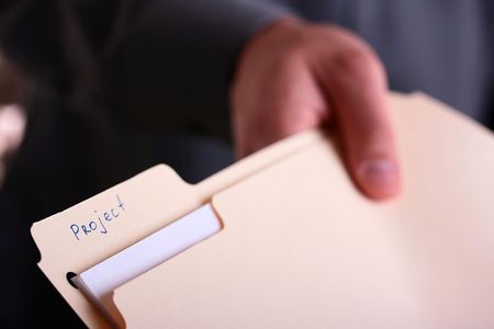 The hand stretches a folder with documents for the project.の写真素材