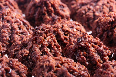 On a white background abreast lie Chocolate flavoured macaroons.