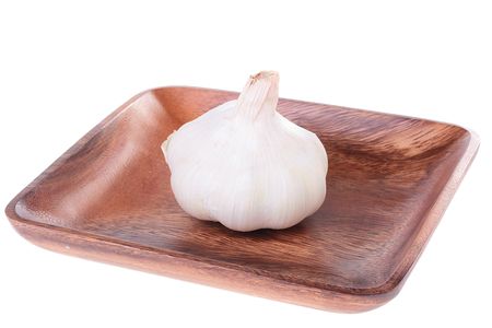 Garlic in a wooden plate on a white background.の写真素材