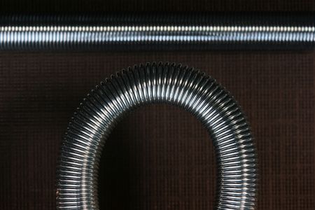 Metal spring deformed on an arch on a brown background.の写真素材