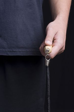 Human hand holding a jump rope on a black background.