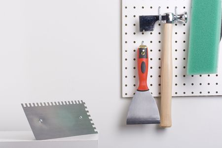 Tools used for wall plastering hanging on a pegboard.