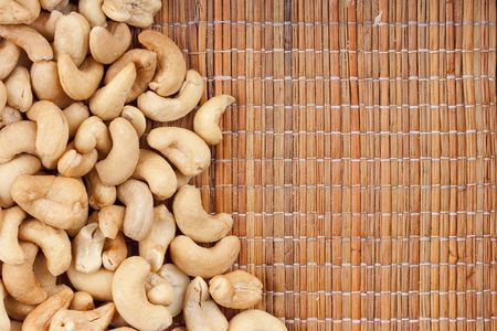 Nuts Cashews are scattered as a background on a wooden mat.の写真素材