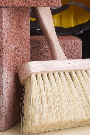 Stonemason's brush next to red bricks and a hard hat.の写真素材