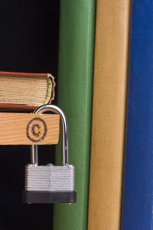 Copyright symbol on a piece of wood attached to a lock by a couple of books.の写真素材